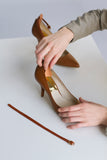 Image of ankle strap being firmly pressed against high heel shoe to demonstrate how to attach the ankle strap